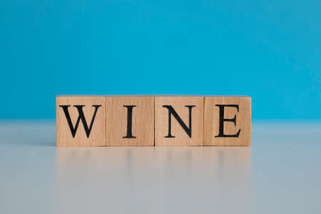 Wine word written on wood cube with blue background. cLOSE UP.
