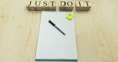 There is a notepad checker and pencil on the table. On the right, it says, Just do it, with a wooden...