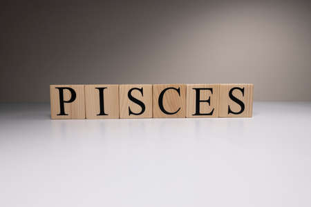 Pisces word on wooden cubes on white background. Photographed in the studio and in spot light. Zodiac or star signs consists of 12 horoscopes.の写真素材
