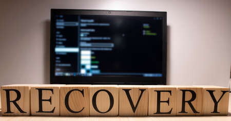 The laptop screen on the table is open. Recovery word from wooden cubes on laptop. Photographs were taken in the spotlight.の写真素材