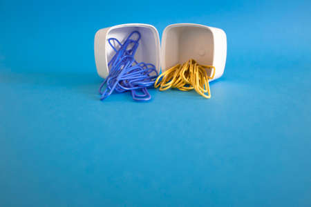 2 plastic white boxes in a row. There are colored paper clips inside. Stationery supplies....