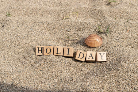 Holiday concept from wooden cubes. Wooden cubes embedded in sand.の写真素材