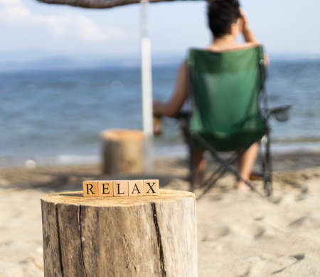 The word relax from wooden cubes. Close-up on the beach sand.の写真素材