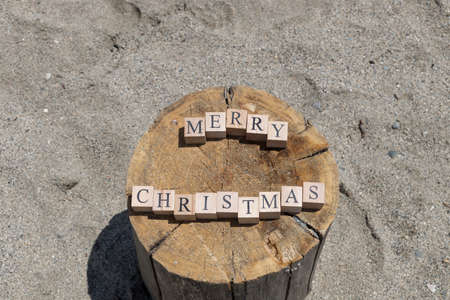 Merry christmas text from wooden cubes. The cubes are on the tree stump.の写真素材