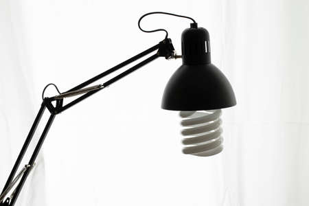 Table lamp in black color. Large spiral lamp is installed. Curtain white window curtain in the background.の写真素材