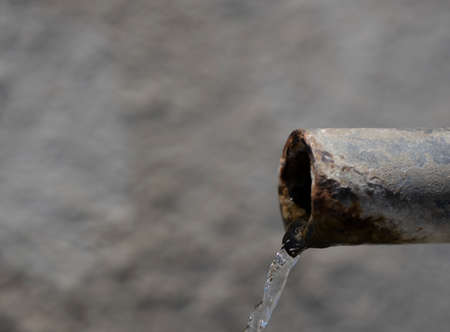 Clean water source in the forest. Iron pipe flows into the small concrete pool. Close up.の写真素材