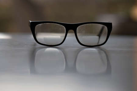 Old dirty black glasses on the desk. It is used to see nearby.の写真素材