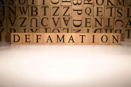 The word defamation end was created from wooden cubes. Countries and politics, people. close up.