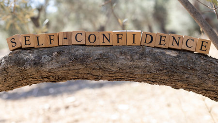 The word self-confidence was created from wooden cubes. Photographed on the tree.. Close-up.の写真素材