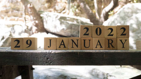 January was created from wooden cubes. Outdoors on table, trees in background. close up.の写真素材