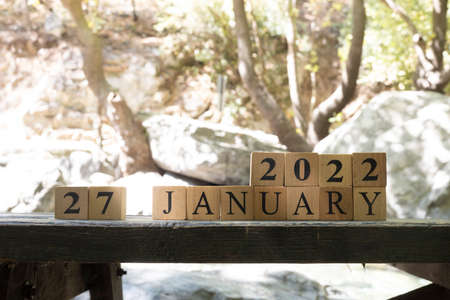 January was created from wooden cubes. Outdoors on table, trees in background. close up.の写真素材