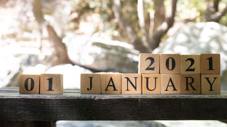 January was created from wooden cubes. Outdoors on table, trees in background. close up.の写真素材