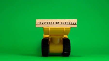 The word Construction laborers is written on wooden sticks. machine concept. job occupations.の写真素材