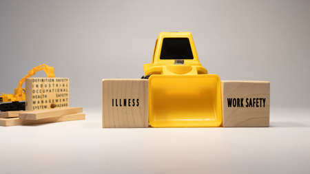 Illness, work safety written on wooden sticks. Business machine and white background concept. Occupational safety and industry.の写真素材