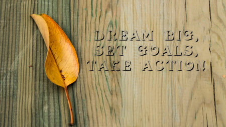 Dream BIG, Set GOALS, Take ACTION phrase. Written on wooden surface. yellowed leaves.の写真素材