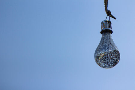 A light bulb against a blue sky. Close up the light bulb. blue sky background. Decorative light...