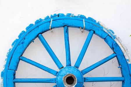 The old wooden wheel on a white wall. Close-up view.The old wooden wheel on the background of the wall of the houseの写真素材