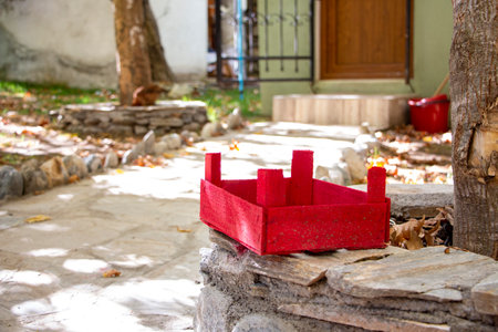 Red wooden basket on a stone in the garden. The red wooden box on a stone wall in the courtyard of the houseの写真素材