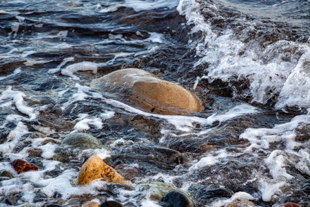 Sea waves and pebbles on the beach. Beautiful seascape.Sea waves crashing on the rocks and forming splashes on the shoreの写真素材