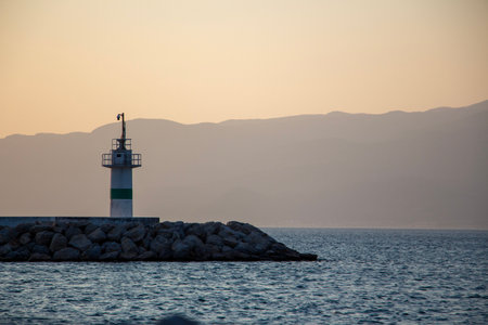 Lighthouse on the coast at sunset. Lighthouse in the harbour. Sunset over the sea and the lighthouse in the harbour.の写真素材