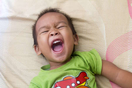 kid having big laugh while laying on bed