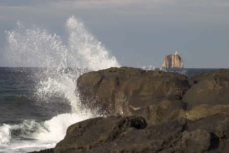 Strombolicchio is a very old vulcanic isle in front of the coast of Stromboli, tthe famous volcanic island. Lava-stones in the foreground,の写真素材
