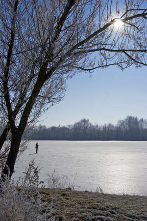man walks over a frozen lake, against sunの写真素材