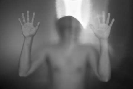 Man behind the matte glass. Blurry hand and body figure abstraction.の写真素材
