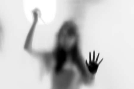 Shadow woman figure with a  scissors behind glass in black  whiteの写真素材