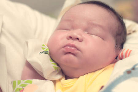 Baby boy infant newborn offspring sleeping on mother hands