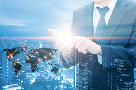 Double exposure of businessman touching with smart phone world business network connection and city center of business, Technology communication business and finance concept,の写真素材
