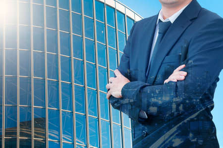 Double exposure of young handsome confident professional businessman standing crossed arms and night cityscape with modern office building background, Business & Real estate agency conceptの写真素材