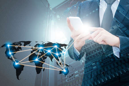 Double exposure of professional businessman using smart phone with servers technology in data center and world map network connection in IT Business concept,の写真素材