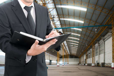 Professional businessman evaluation factory with blurred construction factory building site background, industrial business conceptの写真素材