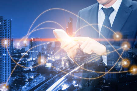 Double exposure of businessman working with smart phone world business network connection and city center of business, communication business and finance conceptの写真素材