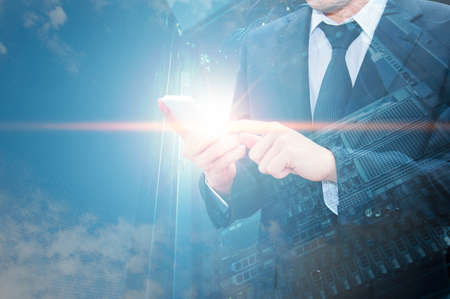Double exposure of professional businessman using cloud technology in smart phone with servers technology in data center and network connection in IT Business technology conceptの写真素材