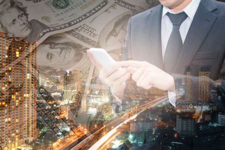 Double exposure of business man working with smart phone and city center of business with bank...