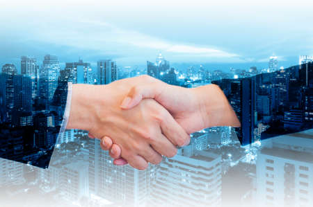 Double exposure of businessman and businesswoman handshake with city of business in blue tone backgroundの写真素材