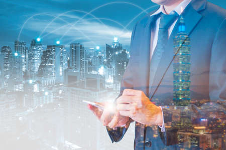 Double exposure of businessman touching with smart phone world business network connection and city center of business, Technology communication business and finance conceptの写真素材