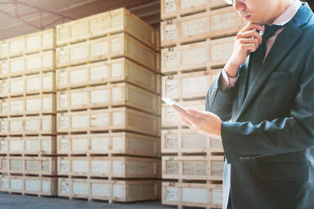 Double exposure of businessman looking smart phone for analyze and checking stock at logistics port background, transportation trading business concept, world map element of this image furnished by NASAの写真素材