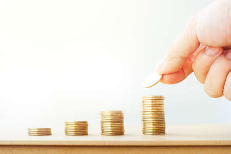 Wealth man put a coin stack on growing money rows of coins growth up on the table with white background in business finance and banking conceptの写真素材