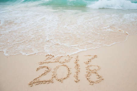 2017 is going end of year and Happy new year 2018 written on sand beach with blue wave, New Year...