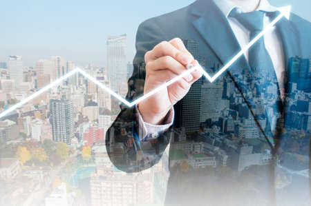 Double exposure of professional businessman with night cityscape drawing growth graph in business conceptの写真素材