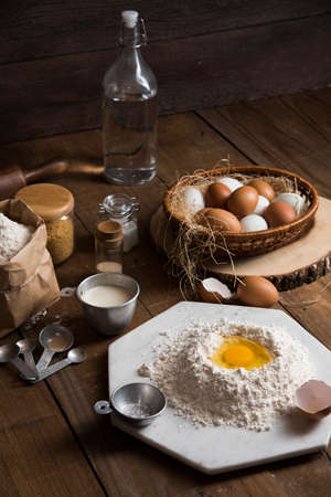 Bakery ingredients : flour, eggs, butter, sugar and rolling pin on vintage wood table, Sweet baking conceptの写真素材