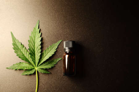 Medicinal cannabis leaf with marijuana oil in bottle on dark background.の写真素材