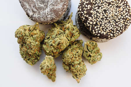 Marijuana blooms and sweets isolated on white background. Cannabis flowers and cookies close up....