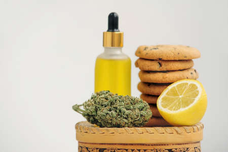 Sweets with CBD oil. Marijuana buds on white background. Cannabis flowers and chocolate cookies close-up.の写真素材
