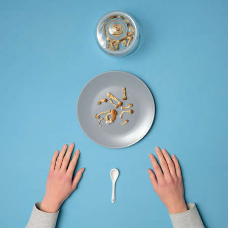 Micro-dosing concept. Lady's hands holding a plate with psilocybe cubensis mushrooms on blue layout. Daily routine. Psilocybin psychedelic magic mushrooms Golden Teacher. Top view, flat lay.の写真素材