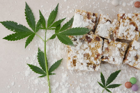Craft sweets with cannabis on ivory background. Layout with marijuana leaves, candy confetti and powdered sugar, top view, flat lay.の写真素材