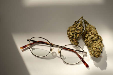 Ophthalmology and cannabis concept. Marijuana buds with glasses on white background. Alternative Glaucoma Therapiesの写真素材